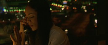 Movie still from “Collateral” (2004), directed by Michael Mann – A woman sitting at a table in front of lights; Close Up shot, High angle