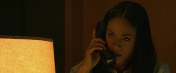 Movie still from “Collateral” (2004), directed by Michael Mann – A woman talking on a phone in a dimly - lit room; Close Up shot, High angle