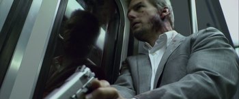 Movie still from “Collateral” (2004), directed by Michael Mann – A man in a suit and tie holding a gun; Close Up shot, Low angle