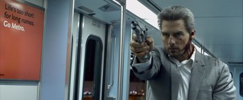Movie still from “Collateral” (2004), directed by Michael Mann – A man holding a gun on top of a train car; Close Up shot, Low angle