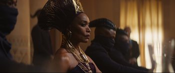 Movie still from “Black Panther: Wakanda Forever” (2022), directed by Ryan Coogler – A woman in a purple and gold headdress; Medium shot, Over the shoulder angle