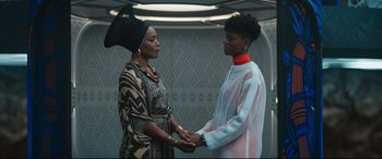 Movie still from “Black Panther: Wakanda Forever” (2022), directed by Ryan Coogler – Two women holding hands in a room; Medium shot, Low angle