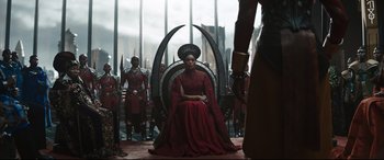 Movie still from “Black Panther: Wakanda Forever” (2022), directed by Ryan Coogler – A woman in a red dress sitting on top of a throne; Wide shot, Over the shoulder angle