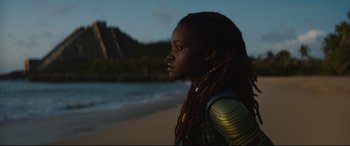 Movie still from “Black Panther: Wakanda Forever” (2022), directed by Ryan Coogler – A woman with dreadlocks standing on the beach; Close Up shot, Over the shoulder angle