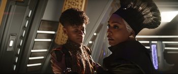 Movie still from “Black Panther: Wakanda Forever” (2022), directed by Ryan Coogler – Two people standing next to each other in a room; Close Up shot, Over the shoulder angle