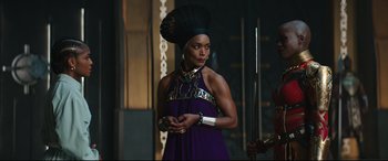 Movie still from “Black Panther: Wakanda Forever” (2022), directed by Ryan Coogler – A woman in a purple dress and a black headpiece; Medium shot, Over the shoulder angle