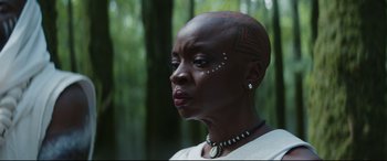 A woman with a shaved head is looking to her left