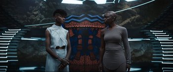 Movie still from “Black Panther: Wakanda Forever” (2022), directed by Ryan Coogler – Two women standing next to each other in front of a painting; Medium shot, Low angle