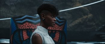 Movie still from “Black Panther: Wakanda Forever” (2022), directed by Ryan Coogler – A black woman with a shaved head looking to her left; Close Up shot, Low angle