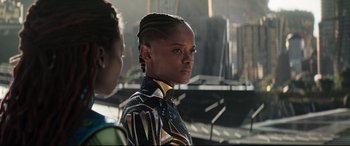Movie still from “Black Panther: Wakanda Forever” (2022), directed by Ryan Coogler – A woman in a yellow and black outfit standing next to another woman in a yellow and black outfit; Close Up shot, Over the shoulder angle