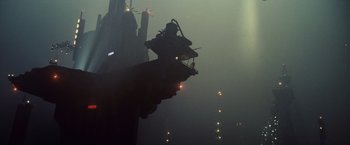 Movie still from “Blade Runner” (1982), directed by Ridley Scott – A view of a building in the fog with lights on it; Extreme Wide shot, Low angle