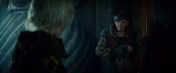 Movie still from “Blade Runner” (1982), directed by Ridley Scott – A man wearing a hat and jacket in a dark room; Medium shot, Over the shoulder angle