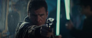 Movie still from “Blade Runner” (1982), directed by Ridley Scott – A man is holding a gun and aiming at the camera; Close Up shot, Over the shoulder angle