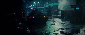 Movie still from “Blade Runner” (1982), directed by Ridley Scott – A car parked on the side of the road in the rain; Wide shot, High angle