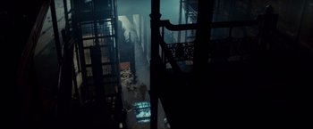 Movie still from “Blade Runner” (1982), directed by Ridley Scott – A person standing in a dark room next to stairs; Extreme Wide shot, High angle