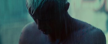 Movie still from “Blade Runner” (1982), directed by Ridley Scott – A man with green hair is standing in the rain; Close Up shot, Low angle