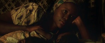 Movie still from “Blood Diamond” (2006), directed by Edward Zwick – A woman laying on a bed with her head wrapped in a scarf; Close Up shot, Overhead angle