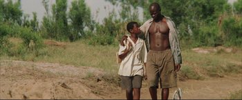 Movie still from “Blood Diamond” (2006), directed by Edward Zwick – A man and a boy walking on a dirt road; Medium shot, Low angle