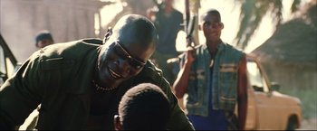 Movie still from “Blood Diamond” (2006), directed by Edward Zwick – A man with sunglasses is laughing with other men; Close Up shot, Over the shoulder angle