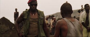 Movie still from “Blood Diamond” (2006), directed by Edward Zwick – A man wearing a red beret and a green jacket; Medium shot, Low angle