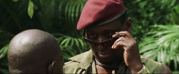 Movie still from “Blood Diamond” (2006), directed by Edward Zwick – A man in a red hat and glasses talking on a cell phone; Close Up shot, Low angle