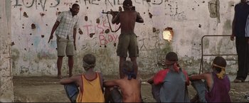 Movie still from “Blood Diamond” (2006), directed by Edward Zwick – A group of men standing around a wall with graffiti on it; Wide shot, Low angle