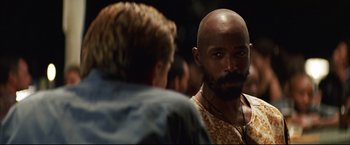 Movie still from “Blood Diamond” (2006), directed by Edward Zwick – A man with a bald head and beard talking to another man; Close Up shot, Over the shoulder angle
