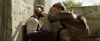Movie still from “Blood Diamond” (2006), directed by Edward Zwick – A man is touching another man's face while sitting on the ground; Medium shot, Over the shoulder angle