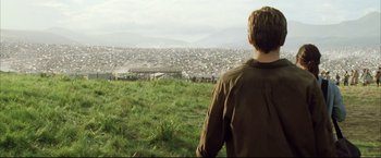 Movie still from “Blood Diamond” (2006), directed by Edward Zwick – A man standing on top of a hill looking over a city; Extreme Wide shot, Over the shoulder angle