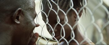 Movie still from “Blood Diamond” (2006), directed by Edward Zwick – A young boy looking through a chain link fence; Close Up shot, Over the shoulder angle