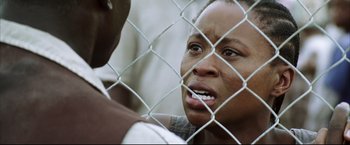 Movie still from “Blood Diamond” (2006), directed by Edward Zwick – A woman is looking through a chain link fence; Close Up shot, Low angle
