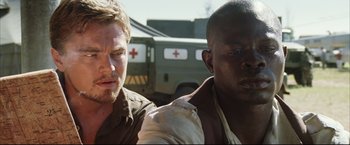 Movie still from “Blood Diamond” (2006), directed by Edward Zwick – Two men are standing next to each other in front of an ambulance; Close Up shot, Low angle
