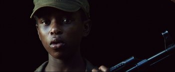 Movie still from “Blood Diamond” (2006), directed by Edward Zwick – A young man holding a cell phone while wearing a hat; Close Up shot, Low angle