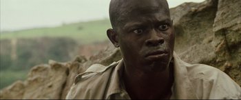 Movie still from “Blood Diamond” (2006), directed by Edward Zwick – A person wearing a brown shirt; Close Up shot, Low angle