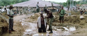 Movie still from “Blood Diamond” (2006), directed by Edward Zwick – A man is shaving another man in the mud; Wide shot, High angle