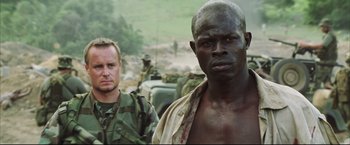 Movie still from “Blood Diamond” (2006), directed by Edward Zwick – Two men standing next to each other in a field; Close Up shot, Over the shoulder angle