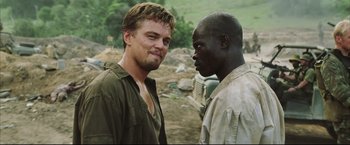 Movie still from “Blood Diamond” (2006), directed by Edward Zwick – Two men are standing next to each other in a field; Close Up shot, Over the shoulder angle