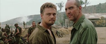 Movie still from “Blood Diamond” (2006), directed by Edward Zwick – Two men standing next to each other on a dirt field; Close Up shot, Over the shoulder angle