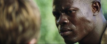 Movie still from “Blood Diamond” (2006), directed by Edward Zwick – A man's face in a forest; Close Up shot, Over the shoulder angle