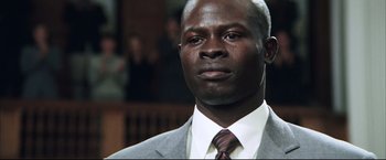 Movie still from “Blood Diamond” (2006), directed by Edward Zwick – A person wearing a suit and tie; Close Up shot, Low angle