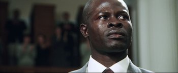 Movie still from “Blood Diamond” (2006), directed by Edward Zwick – A man in a white suit and a red tie; Close Up shot, Low angle
