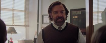 Movie still from “Booksmart” (2019), directed by Olivia Wilde – A man with long hair and a beard wearing a sweater vest; Close Up shot, Over the shoulder angle