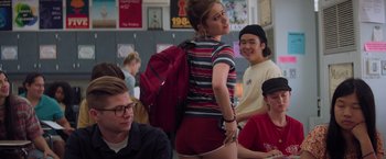 Movie still from “Booksmart” (2019), directed by Olivia Wilde – A woman with a backpack is posing for a picture; Medium shot, Over the shoulder angle