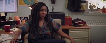 Movie still from “Booksmart” (2019), directed by Olivia Wilde – A woman sitting in a chair with long dreads; Close Up shot, Over the shoulder angle