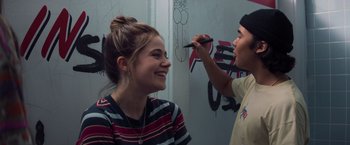 Movie still from “Booksmart” (2019), directed by Olivia Wilde – A young man and a young woman smiling at each other; Medium shot, Over the shoulder angle