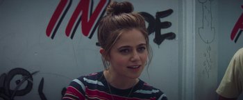 Movie still from “Booksmart” (2019), directed by Olivia Wilde – A woman with a bun in front of a wall; Close Up shot, Over the shoulder angle