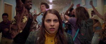Movie still from “Booksmart” (2019), directed by Olivia Wilde – A woman in a yellow jacket is in a crowded room; Close Up shot, Over the shoulder angle