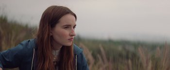 Movie still from “Booksmart” (2019), directed by Olivia Wilde – A woman with long red hair is standing in a field; Close Up shot, Over the shoulder angle