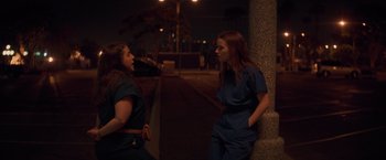 Movie still from “Booksmart” (2019), directed by Olivia Wilde – Two young women are standing next to each other on the sidewalk; Medium shot, Over the shoulder angle