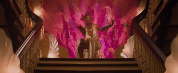 Movie still from “Booksmart” (2019), directed by Olivia Wilde – A woman is sitting on a stage wearing a dress; Medium shot, Low angle